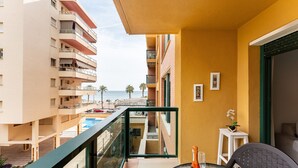 A balcony with a glass table, a bottle, and a chair.