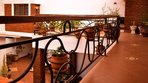 Une terrasse sur le toit, agrémentée d’une balustrade en fer forgé, de plantes en pot et d’un mur en briques.