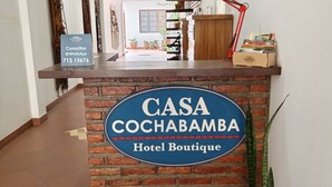Un comptoir d’accueil avec une pancarte indiquant : « CASA COCHABAMBA, hôtel de charme ».