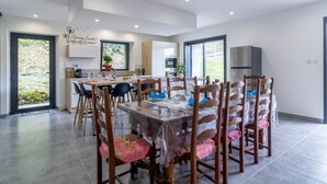 Een moderne eetruimte met een ronde tafel, houten stoelen en een keuken op de achtergrond.