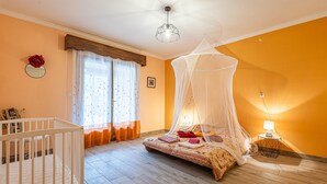 Ein Schlafzimmer mit einem Himmelsbett, einem Babybett und einer Nachttischlampe.