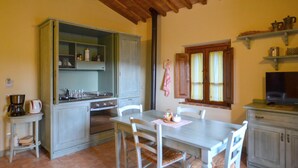 A kitchen with a dining table, chairs, a stove, and a television. - Pet friendly apartment (Ponte alla Piera)