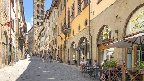 A cobblestone street lined with historic buildings, outdoor seating at cafes, and a prominent clock tower. - Pet friendly apartment (Ponte alla Piera)