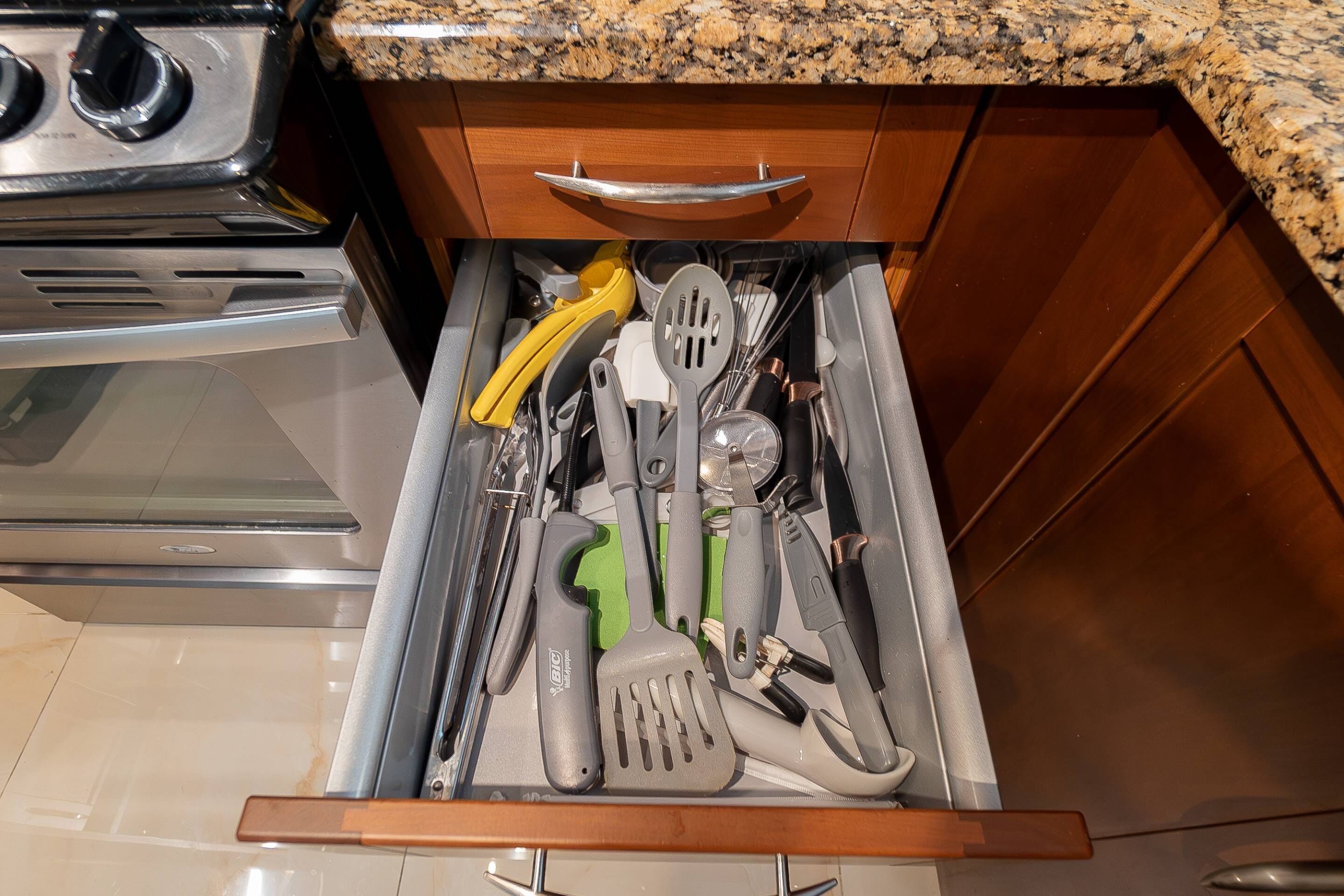 Un cajón con utensilios de cocina, incluyendo una espátula amarilla, una espátula verde y una espátula gris.