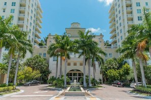 A modern hotel with a central fountain, surrounded by palm trees and multiple floors of balconies. - 316s Serenity by the Sea Suite, 1 Bedroom and 2 Murphy Beds Close to Beach, Shops & Restaurants, Dog Friendly (Boynton Beach)