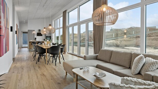 A spacious living area with a large window, a dining area, and a modern kitchen.