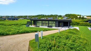 A modern building with a flat roof, large windows, and a paved area with outdoor seating.