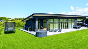 A modern house with a large glass door, outdoor seating, and a trampoline.