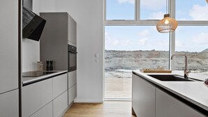 A modern kitchen with a large window, a built-in oven, and a wooden countertop.