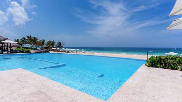 A clear blue swimming pool with a view of the beach and ocean.