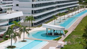 A modern hotel with multiple floors, a central pool area, and outdoor seating. - Airbn Be Luxe Best Golf  view Cana Rock Star E 304 (Bavaro)