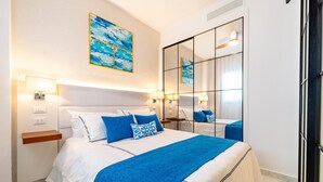 Ein modernes Hotelzimmer mit einem großen Bett, Nachttischlampen, einem Spiegel und einem Bild an der Wand.