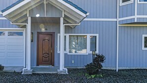 A two-story house with a front porch, a garage, and a small garden area. - Hilo Manu Iki Guest house (Hilo)