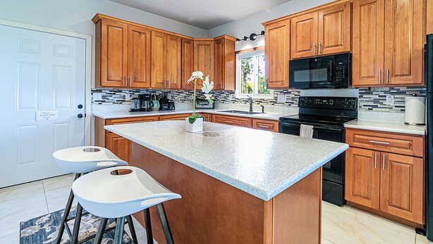 A modern kitchen with wooden cabinets, a large island, and stainless steel appliances. - Hilo Manu Iki Guest house (Hilo)
