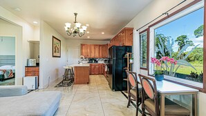 A spacious kitchen with wooden cabinets, a central island, and a dining area with a table and chairs. - Hilo Manu Iki Guest house (Hilo)