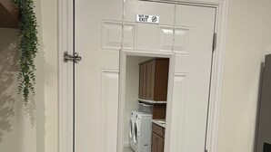 A white door with a 'NOT AN EXIT' sign, a wooden floor, a washing machine, and a cabinet in the background. - Cozy, private full Guesthouse in Bakersfield, CA (Bakersfield)