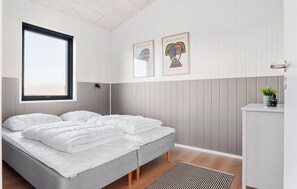 Un dormitorio moderno con una cama, un ventanal y dos obras de arte enmarcadas en la pared.