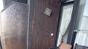 A glass-top table with metal legs, a cushioned chair, and a wooden bench on a tiled patio. - LDL-LUSIV 1-room apartment 2 ground floor with staircase lyft (Bad Camberg)