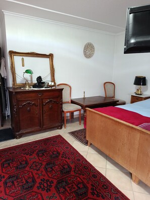 A bedroom with a wooden bed, a dresser, a chair, a desk, and a television mounted on the wall. - LDL-LUSIV 1-room apartment 2 ground floor with staircase lyft (Bad Camberg)