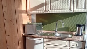 A compact kitchen with wooden cabinets, a microwave, a sink, and a Bosch coffee maker. - LDL-LUSIV 1-room apartment 2 ground floor with staircase lyft (Bad Camberg)