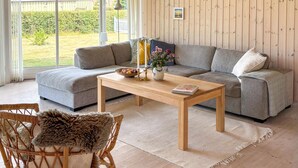 A modern living room with a sofa, a wooden coffee table, and a wicker chair. - Nice home in Væggerløse with WiFi (Væggerløse)