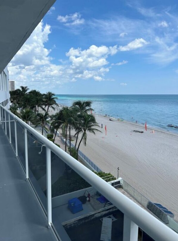 A balcony with a view of a beach, palm trees, and the ocean. - Panoramic Beachfront Views! (Hollywood)