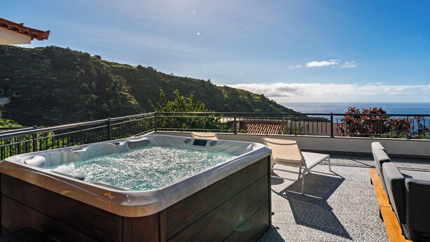 A hot tub on a balcony with a view of a mountainous landscape.