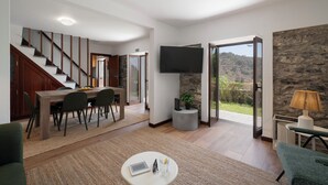 A modern living room with a staircase, a dining area, and a large TV.