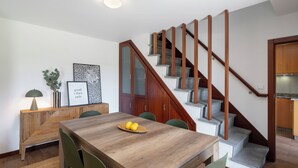 A modern kitchen with a built-in oven, a wooden staircase, and a dining area with a wooden table and chairs.