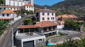 A hillside residential area with a mix of modern and traditional architecture, including a prominent tower.