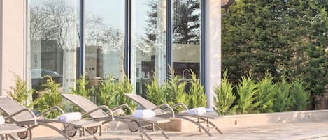 Un espace piscine moderne, doté de chaises longues et offrant une vue dégagée sur la piscine.