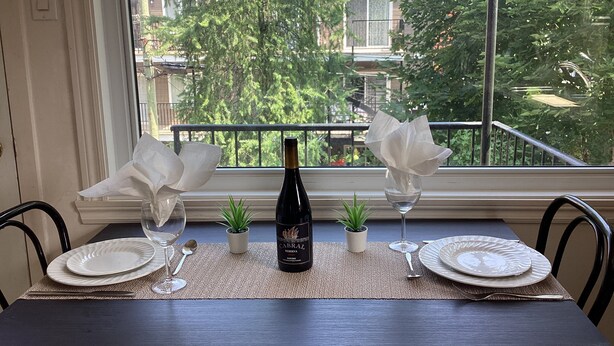 A dining table set with plates, glasses, a bottle, and a small plant. - Bright cosy apartment short walk to metro green line near Olympic Village    (Montréal)