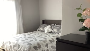 A bedroom with a bed, a nightstand, and a potted plant. - Bright cosy apartment short walk to metro green line near Olympic Village    (Montréal)