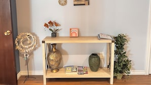 Una consola de madera con objetos decorativos, un florero, un cartel de bienvenida y una planta en maceta.