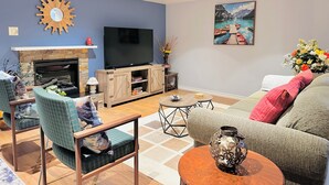 Una sala de estar con chimenea, televisor de pantalla plana, sofá y una mesa de centro.