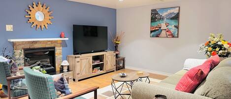 Un salon avec une cheminée, un téléviseur à écran plat, un canapé et une table basse.