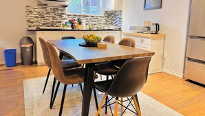 Una cocina moderna con una mesa de comedor de madera, sillas negras y un cuenco de frutas.