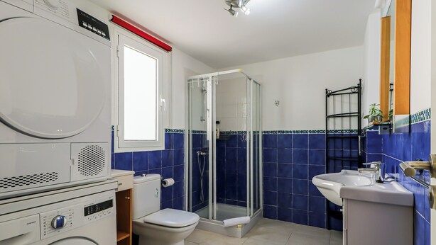 A compact bathroom with a washing machine, toilet, and shower enclosure. - La Palmita Sea Views Agaete (Agaete)