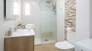 Et moderne badeværelse med brusebad, toilet og vaskebord.