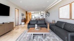 En moderne stue med sofa, sofabord og et fladskærms-tv.