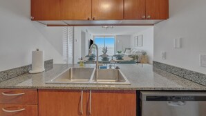 Una cocina con encimeras de granito, armarios de madera y lavavajillas.