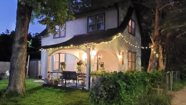 Una casa amb un porxo cobert, llums de garlandes i una taula de menjador.