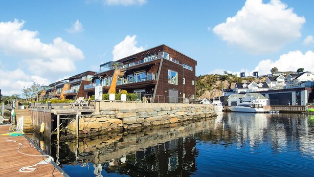 Una propiedad frente al agua con un edificio moderno de varios pisos, un muelle y barcos.