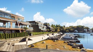Una propiedad frente al agua con arquitectura moderna, un muelle con barcos y una vista despejada del agua.