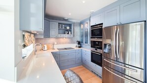 Una cocina moderna con gabinetes grises, electrodomésticos de acero inoxidable y un horno empotrado.
