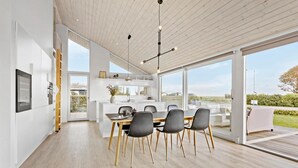 A modern kitchen with a dining area, large windows, and a view of the outdoors. - Cozy home in Sæby with house sea view (Sæby)