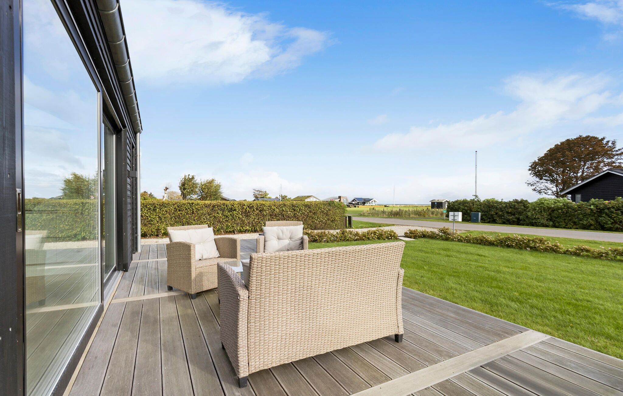 Eine Terrasse im Freien mit Korbmöbeln und Blick auf eine grüne Landschaft.