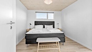 A modern bedroom with a bed, bedside tables, a window, and a ceiling light. - Cozy home in Sæby with house sea view (Sæby)