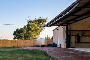 Un espacio al aire libre cubierto, con cerca de madera, una parrilla y un banco.