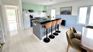 Una cocina moderna con una isla central, taburetes de bar y una zona de comedor con mesa y sillas.